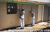 image: Students hammer siding on a home in Mississippi